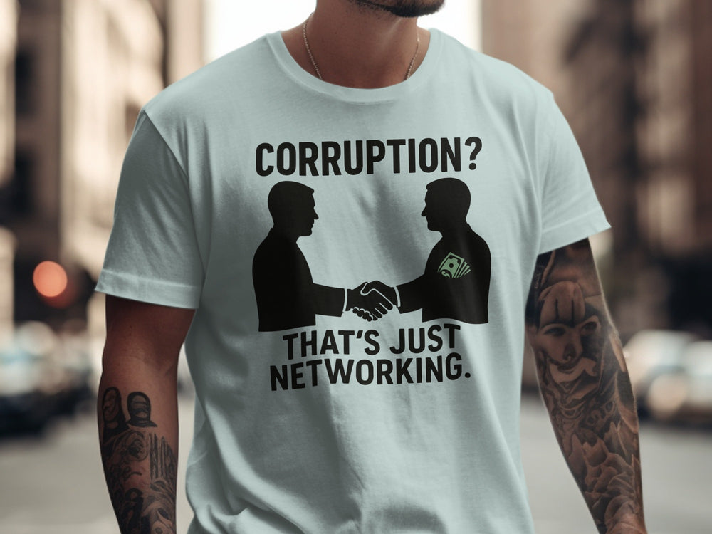 Person wearing a light blue t-shirt with a graphic and text 'Corruption? That's just networking.' on a city street background.