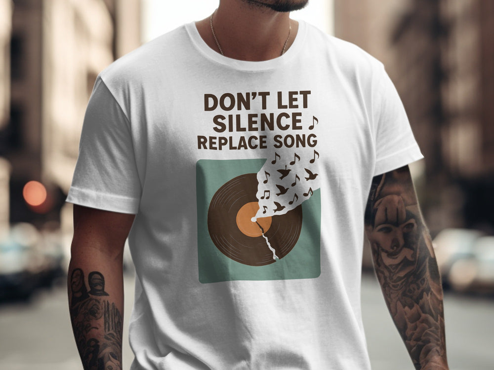 Person wearing a white t-shirt with a graphic and text 'Don't Let Silence Replace Song' in an urban setting.