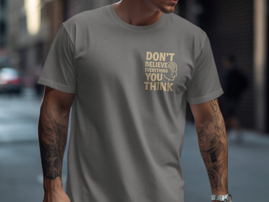 Person wearing a charcoal t-shirt with a motivational quote on a city street.