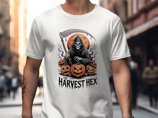 Person wearing a white t-shirt with a graphic design of a skeleton holding a scythe and pumpkins, with 'The Harvest Hex' text.