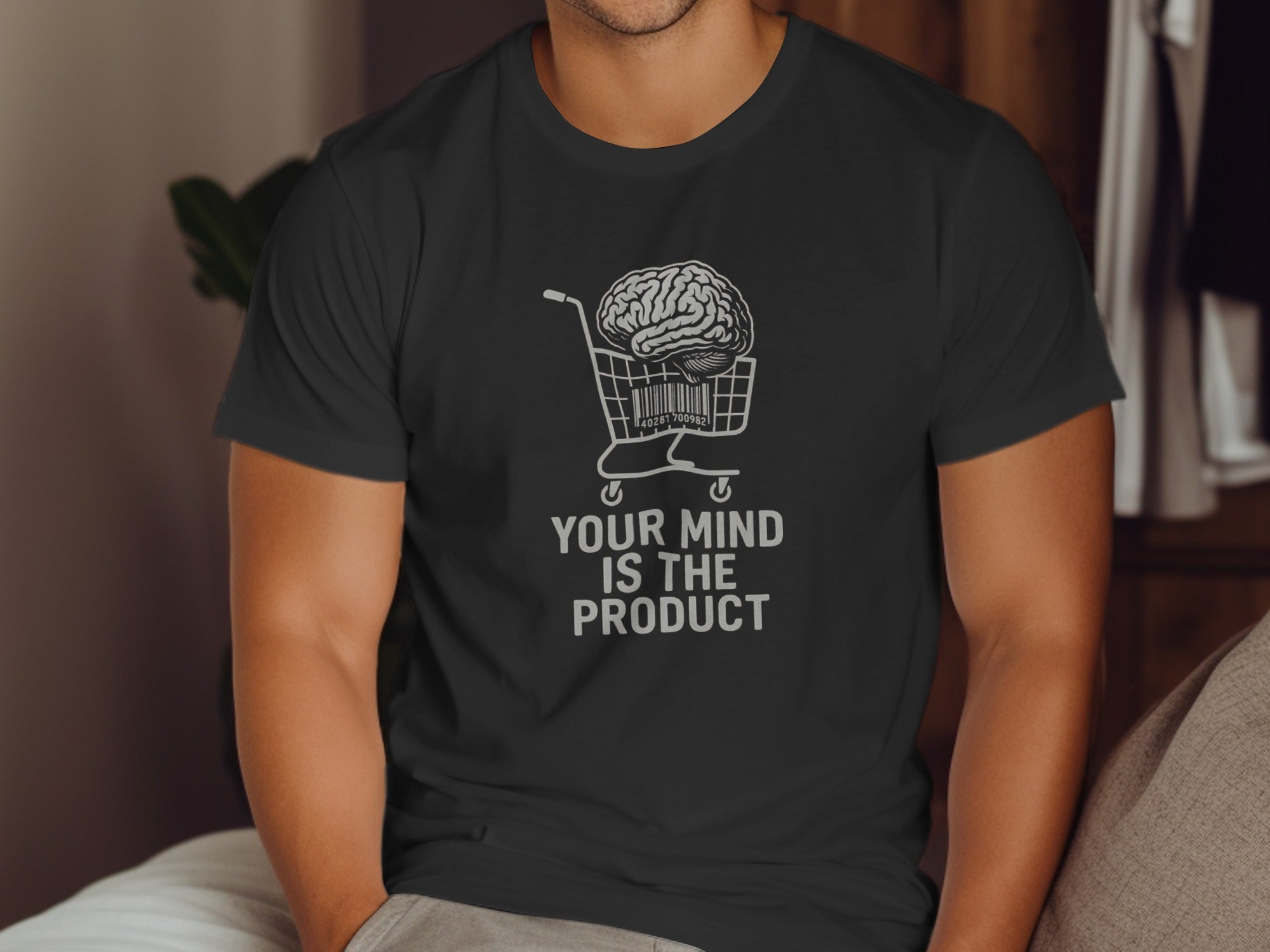 Person wearing a black t-shirt with a graphic and text 'Your mind is the product'.