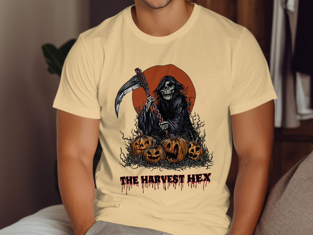 Person wearing a beige t-shirt with a graphic design of the Grim Reaper and pumpkins, labeled 'The Harvest Hex'.