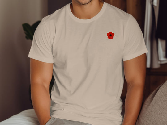 Person wearing a beige t-shirt with a red poppy emblem.