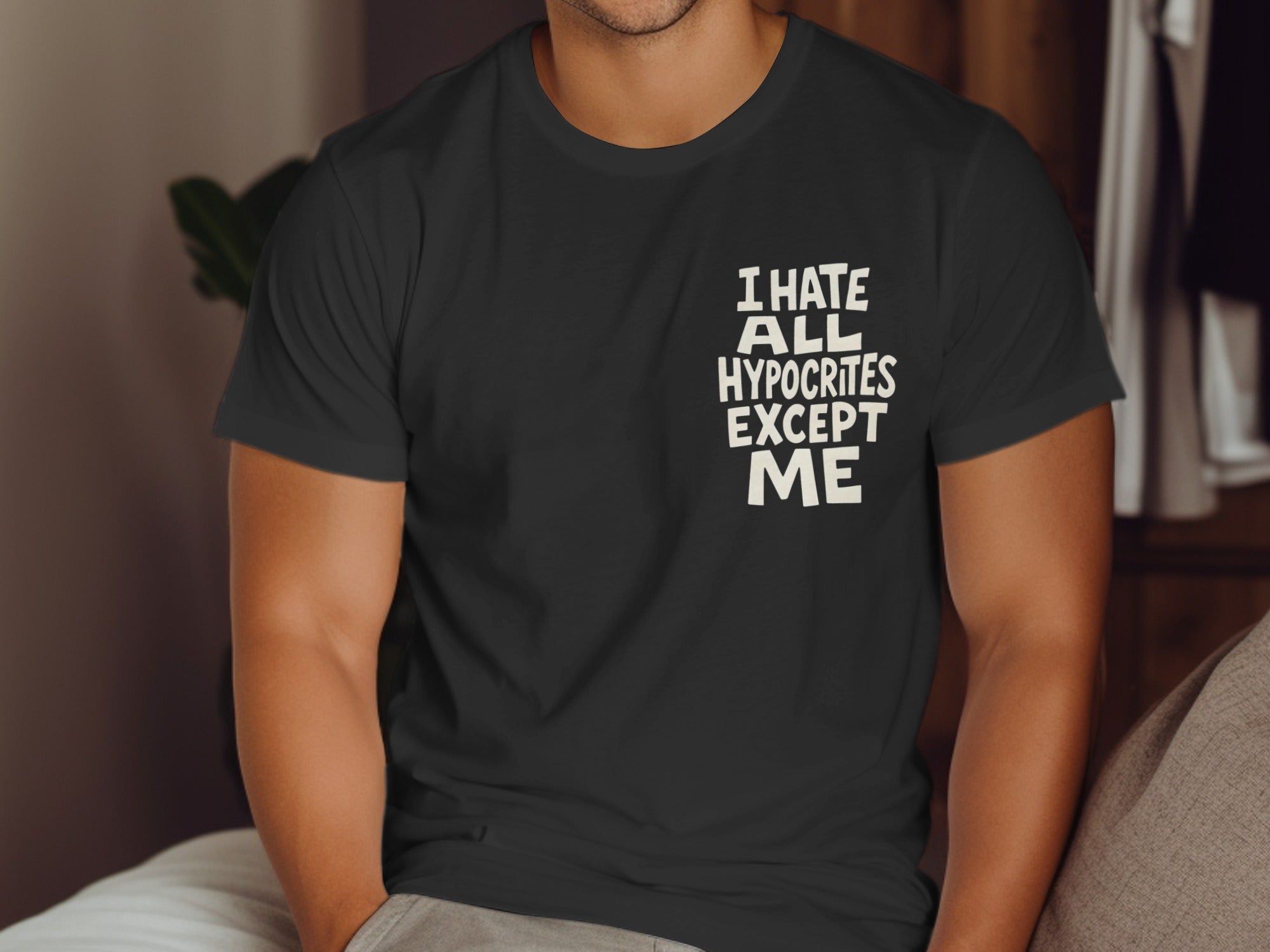 Person wearing a black t-shirt with text sitting on a couch.