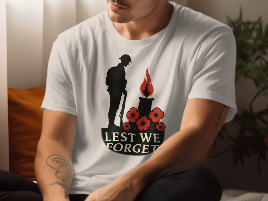 Person wearing a natural color t-shirt with a 'Lest We Forget' design featuring a soldier, candle, and poppies.