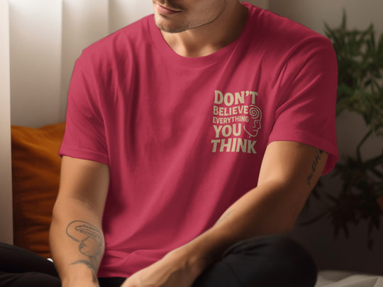 Person wearing a red t-shirt with text sitting indoors.
