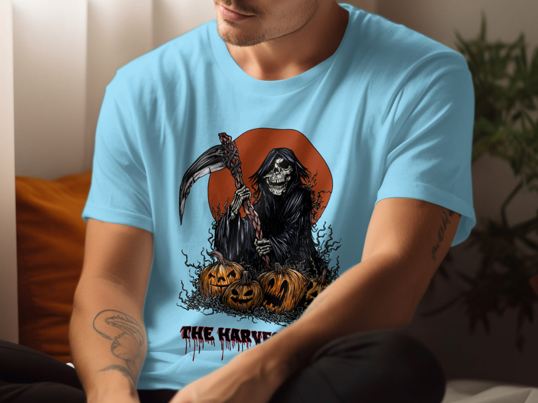 Person wearing a sky blue t-shirt with a graphic design of the Grim Reaper and pumpkins.