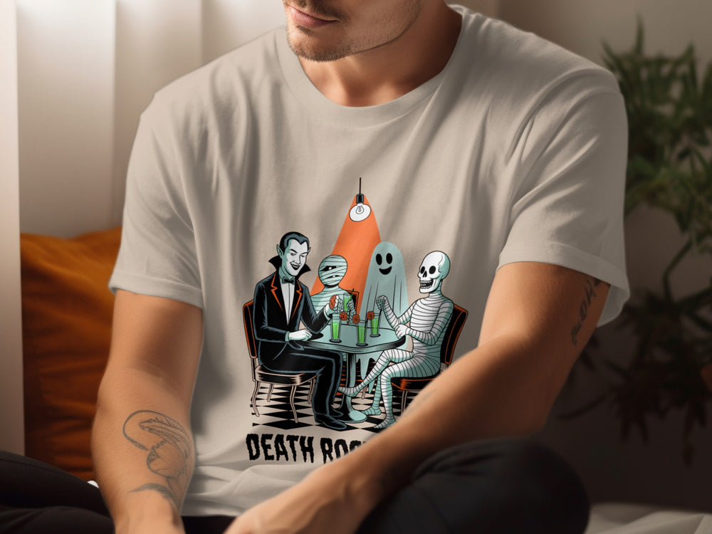 Person wearing a sand color t-shirt with a graphic design of skeletons at a table with a bottle labeled 'Death Row'.