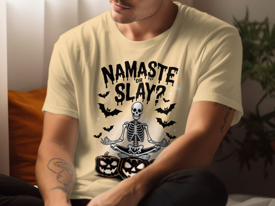 Person wearing a yellow t-shirt with a skeleton and pumpkins design and text 'Namaste or Slay?'