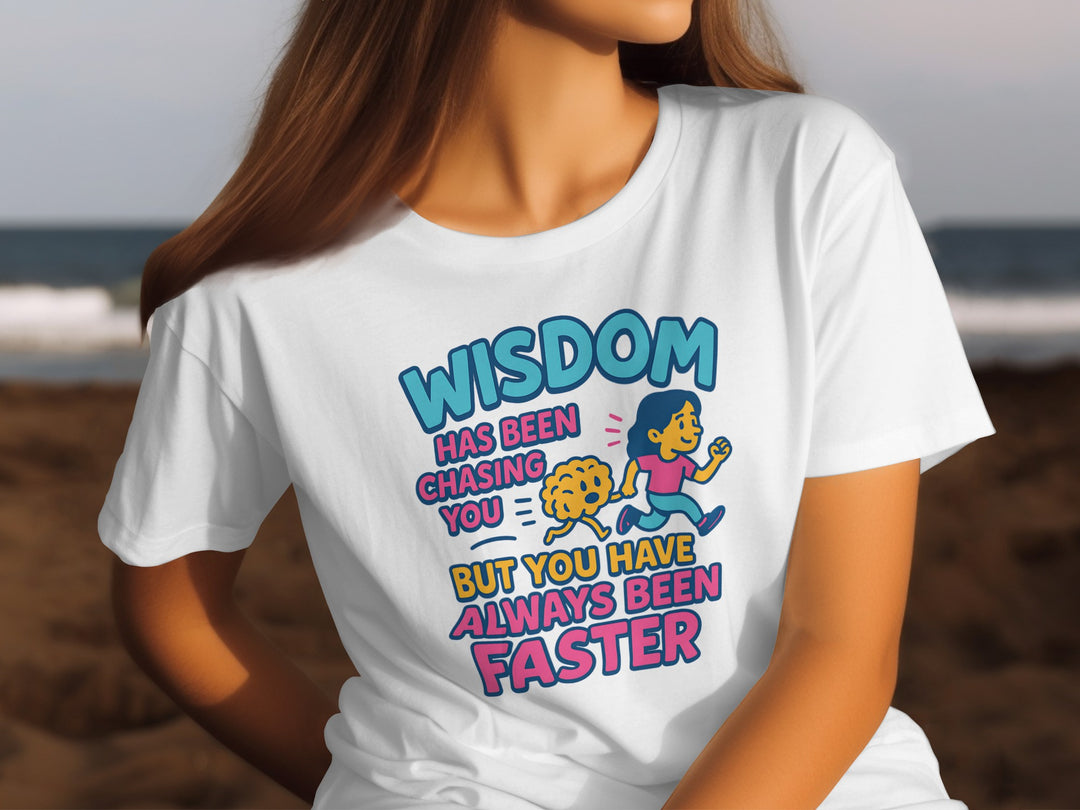 Person wearing a white t-shirt with a colorful graphic and text on a beach.