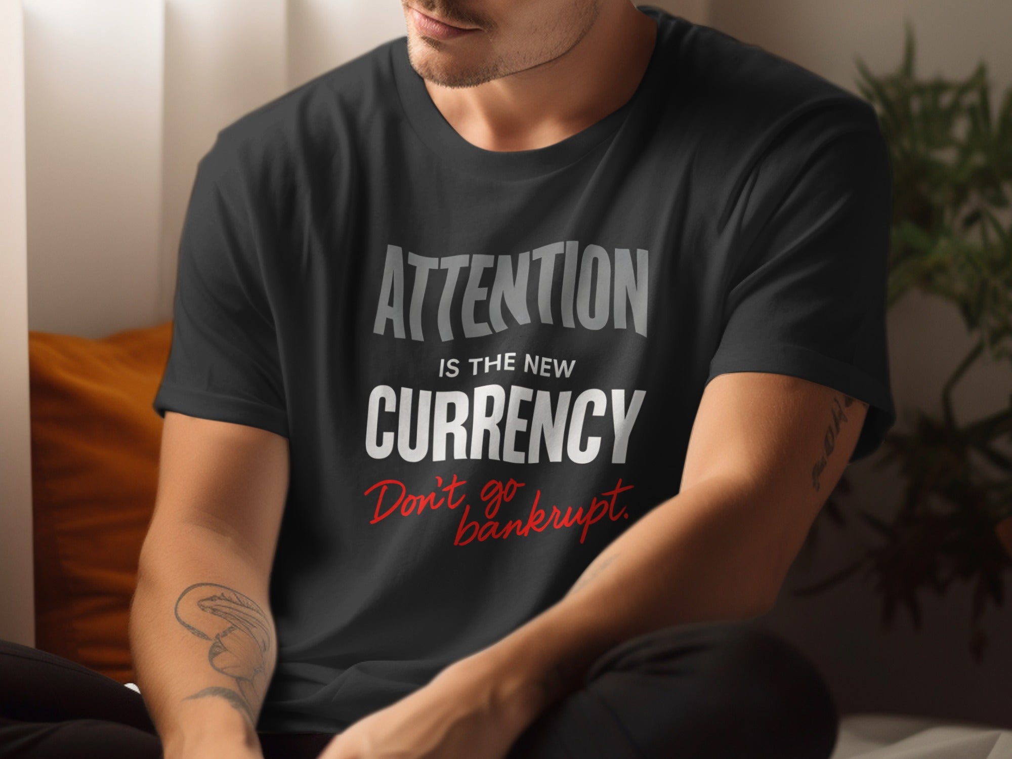 Person wearing a black t-shirt with text 'Attention is the new currency. Don't go bankrupt.'