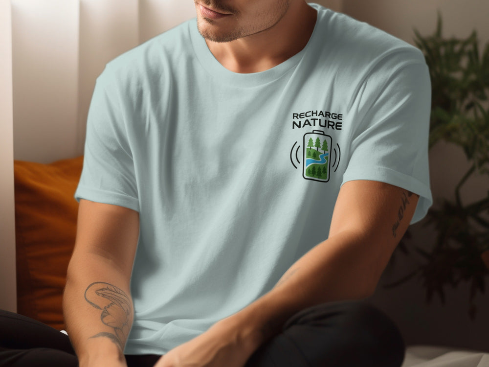 Person wearing a light blue t-shirt with a logo and text, sitting indoors.