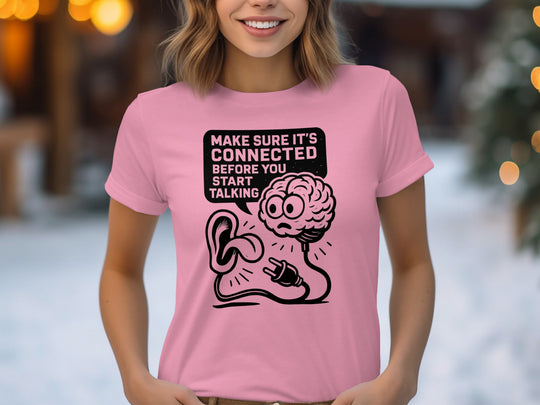Person wearing a pink t-shirt with a graphic design and text.