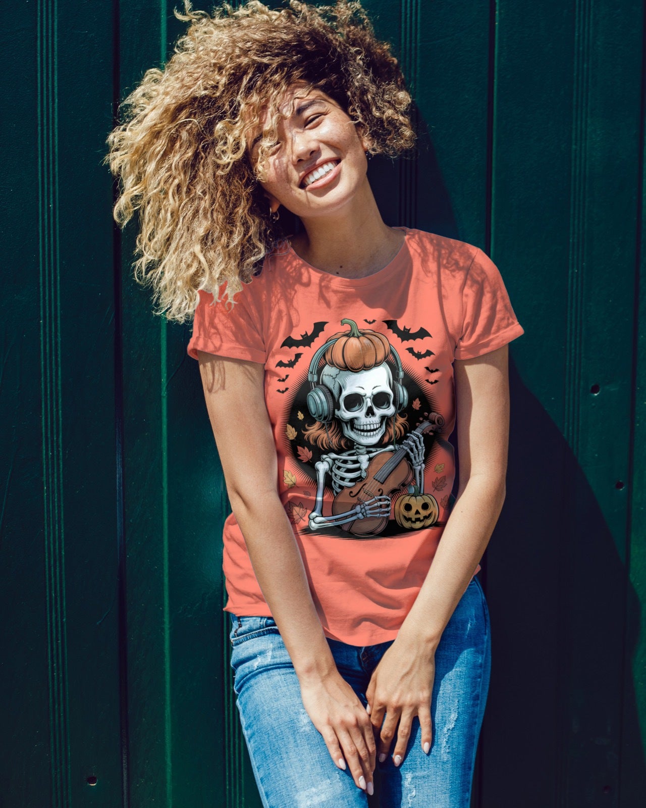 Women wearing a Halloween-themed t-shirt with a skeleton and pumpkin design against a dark background.