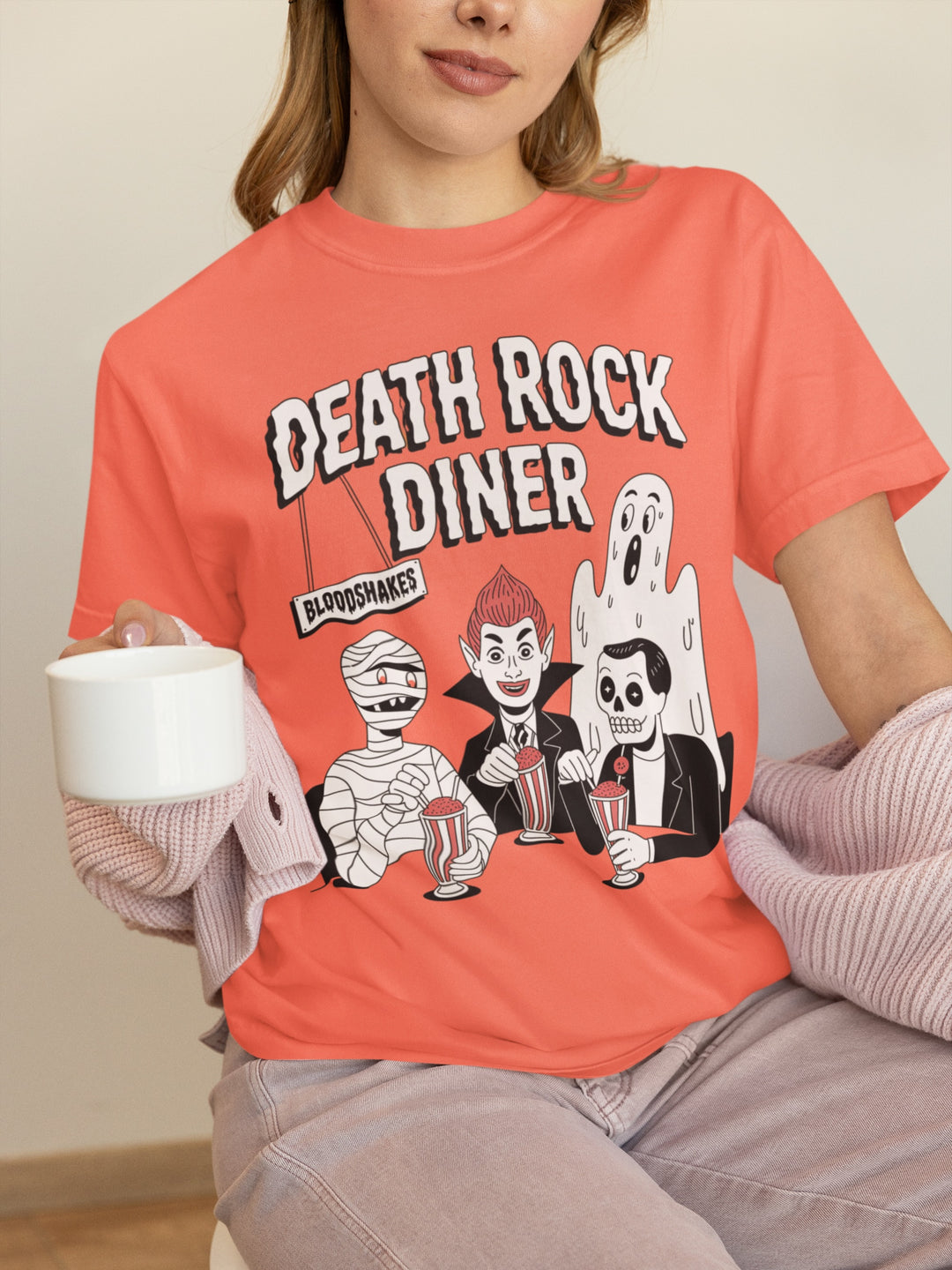 Person wearing an orange 'Death Rock Diner' t-shirt with cartoon characters.
