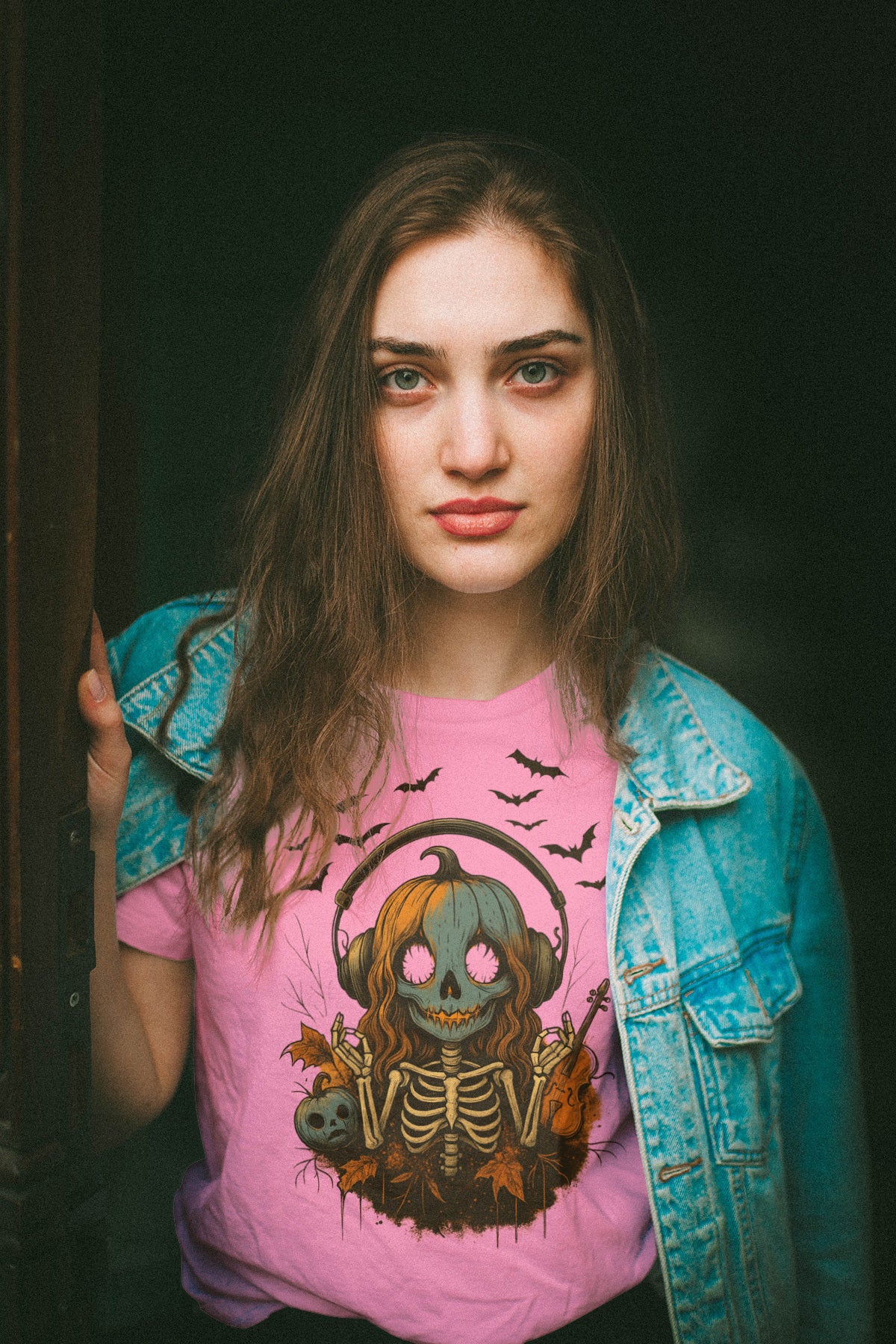 Women wearing a pink t-shirt with a graphic design, standing against a dark background